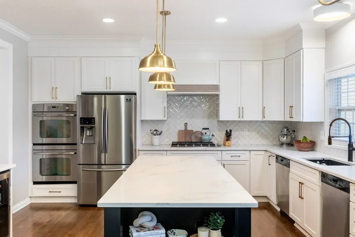 Kitchen after cabinet refacing, with new white shaker door fronts, quartz countertops, a black island and stainless double wall ovens