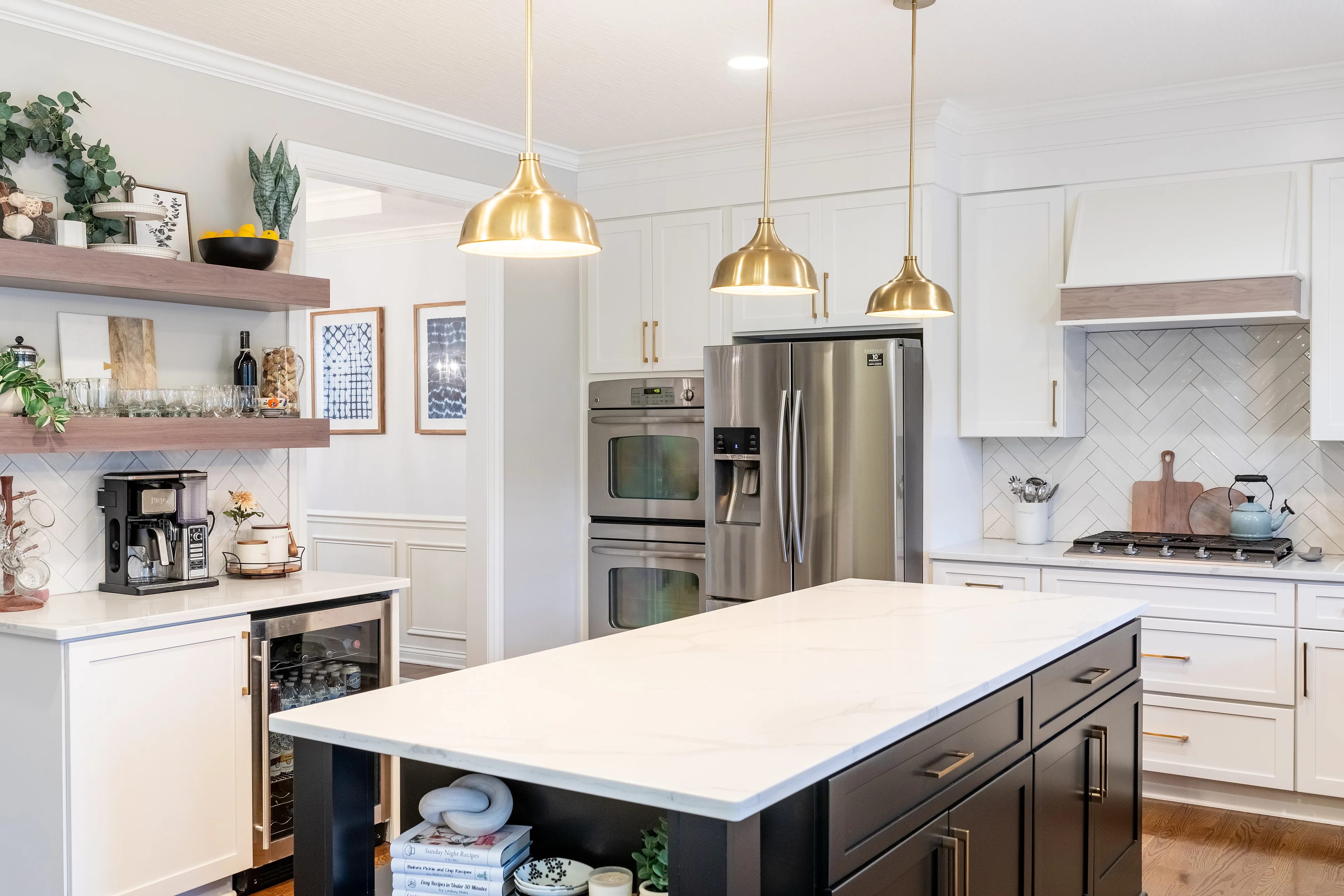 Finished Columbus kitchen with a black quartz-topped island, brass dome pendants, stained floating shelves over a coffee bar and stainless double wall ovens