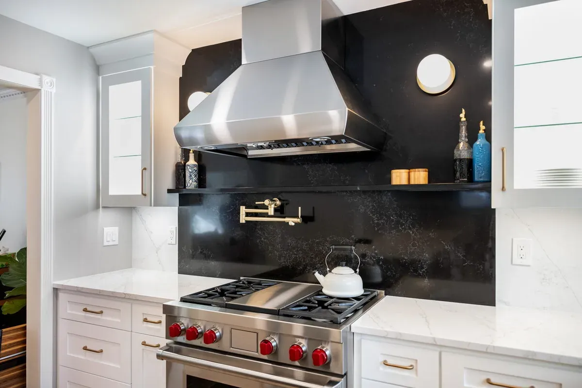 Custom kitchen cabinetry framing a professional stainless range beneath a stainless hood and a dark soapstone-look backsplash
