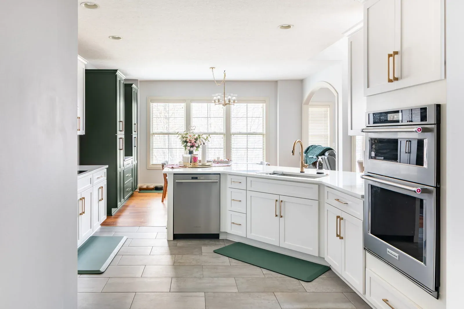 Westerville kitchen remodel with white shaker cabinets, quartz counters, a stainless wall oven stack and a hunter green pantry at the far end